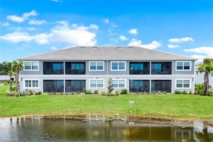 Rear view of property with a water view, a tile roof, a yard, and stucco siding