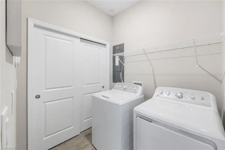 Laundry area featuring independent washer and dryer, electric panel, and light wood-style flooring