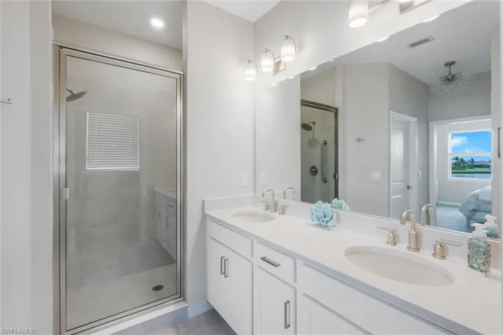 Ensuite bathroom featuring double vanity and a shower stall