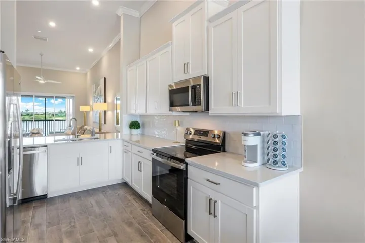 Kitchen with appliances with stainless steel finishes, backsplash, ornamental molding, light wood-type flooring, and light countertops