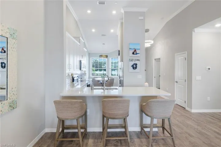 Kitchen featuring crown molding, light wood-type flooring, light countertops, a kitchen breakfast bar, and a peninsula