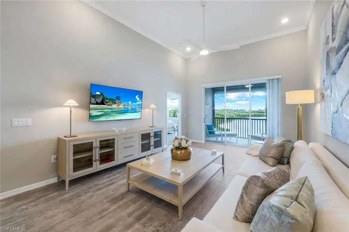 Living room featuring crown molding, wood finished floors, a high ceiling, and ceiling fan