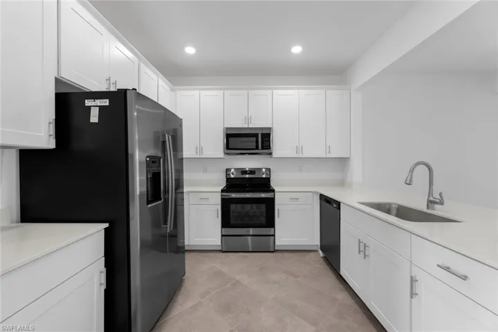 Kitchen with stainless steel appliances, white cabinetry, light countertops, recessed lighting, and light tile patterned floors