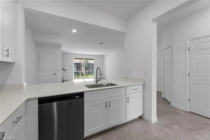 Kitchen featuring dishwasher, a peninsula, white cabinetry, light countertops, and recessed lighting