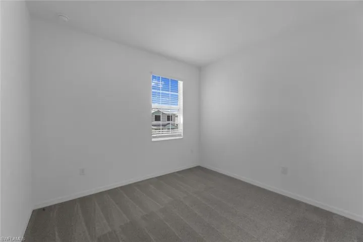 Unfurnished room featuring dark carpet and a smoke detector