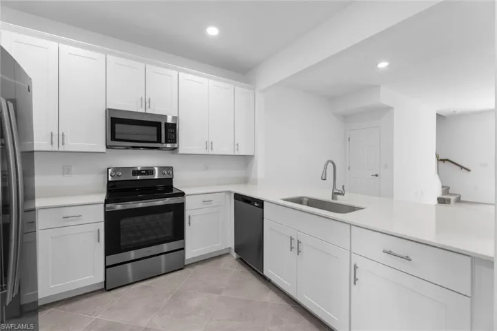 Kitchen with appliances with stainless steel finishes, light countertops, white cabinets, recessed lighting, and light tile patterned flooring