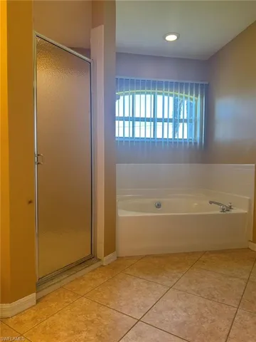 Bathroom featuring a garden tub, a stall shower, and light tile patterned floors