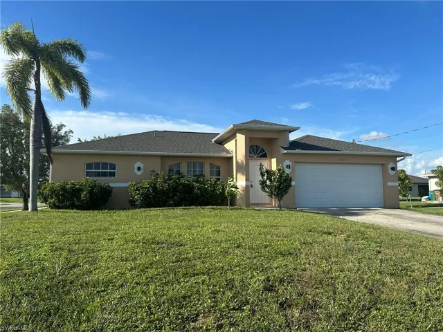 View of front of home featuring stucco siding, driveway, a front lawn, and a garage