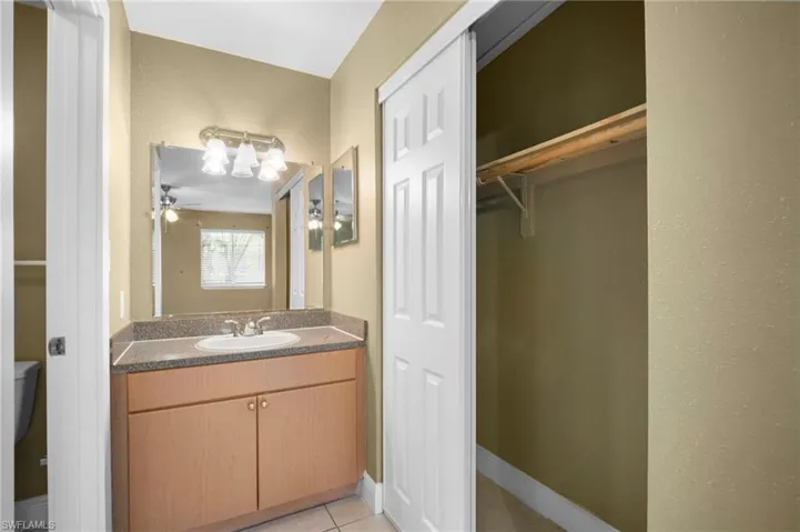 Bathroom featuring vanity, a spacious closet, light tile patterned floors, and a textured wall