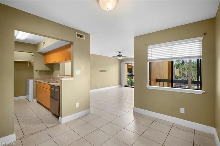 Kitchen with light countertops, stainless steel dishwasher, light tile patterned floors, a ceiling fan, and washer / clothes dryer