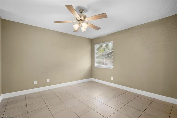 Empty room featuring a ceiling fan and light tile patterned floors