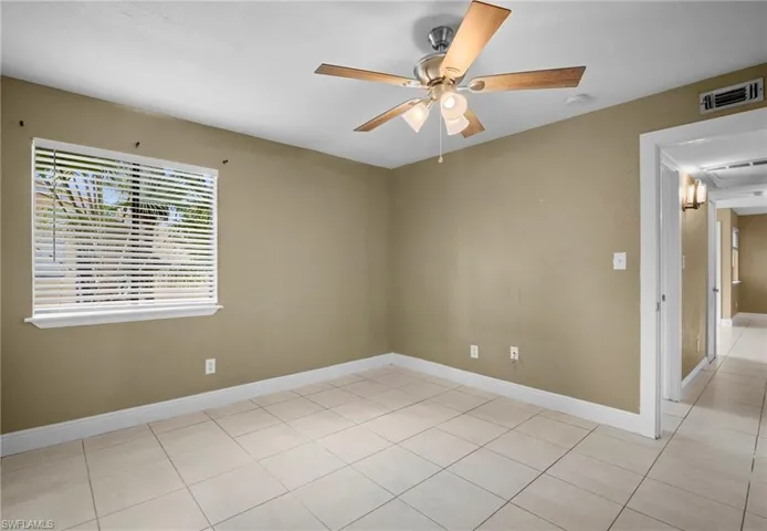 Empty room with a ceiling fan and light tile patterned floors