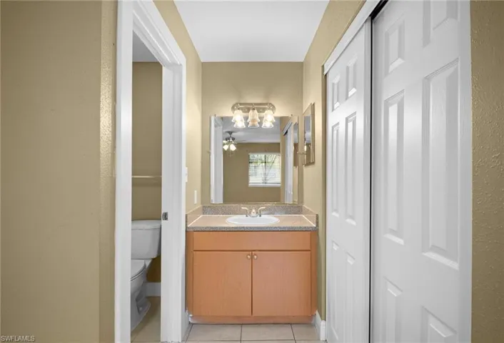 Bathroom with vanity, a textured wall, and light tile patterned flooring