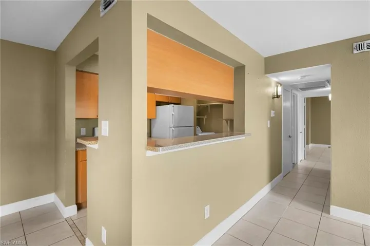 Hallway featuring light tile patterned floors and baseboards