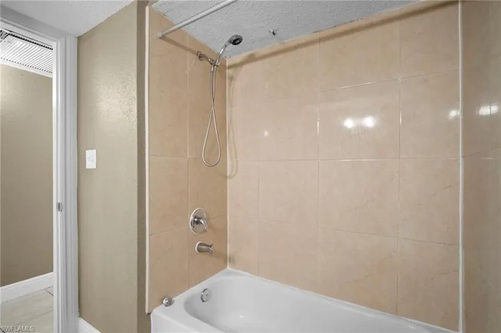 Full bath featuring bathtub / shower combination and a textured wall