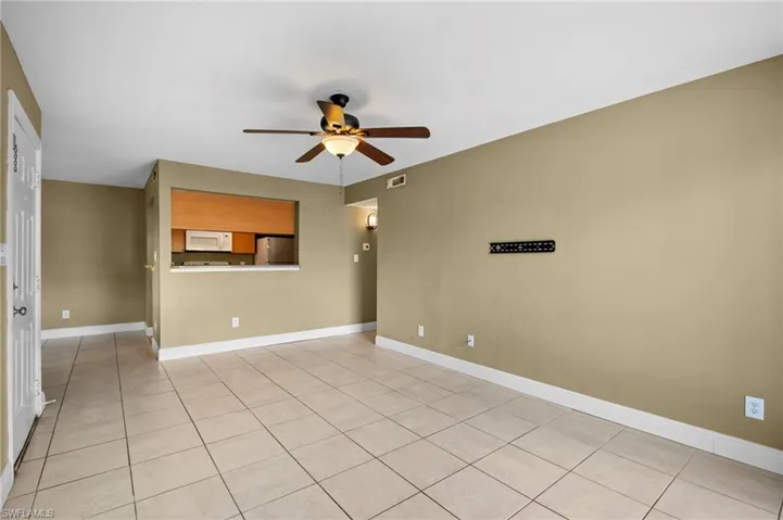 Empty room with a ceiling fan and light tile patterned floors
