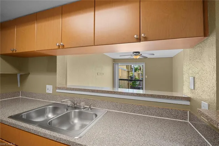 Kitchen with a textured wall, a ceiling fan, and brown cabinetry
