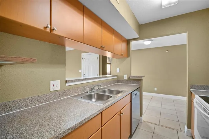 Kitchen featuring a textured wall, light tile patterned floors, dishwasher, white electric stove, and light countertops