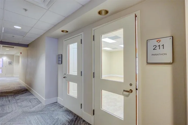 Common area hallway corridor with light carpet and a paneled ceiling