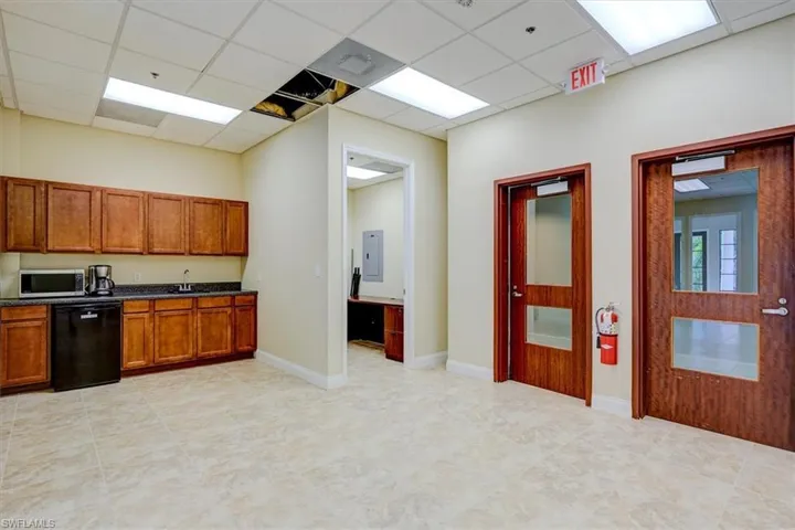 Kitchen featuring dishwasher, brown cabinetry, stainless steel microwave, a drop ceiling, and electric panel