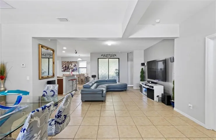 Living room with beamed ceiling and light tile flooring