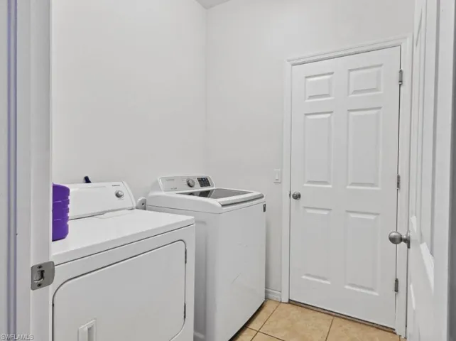 Laundry area featuring separate washer and dryer and light tile floors