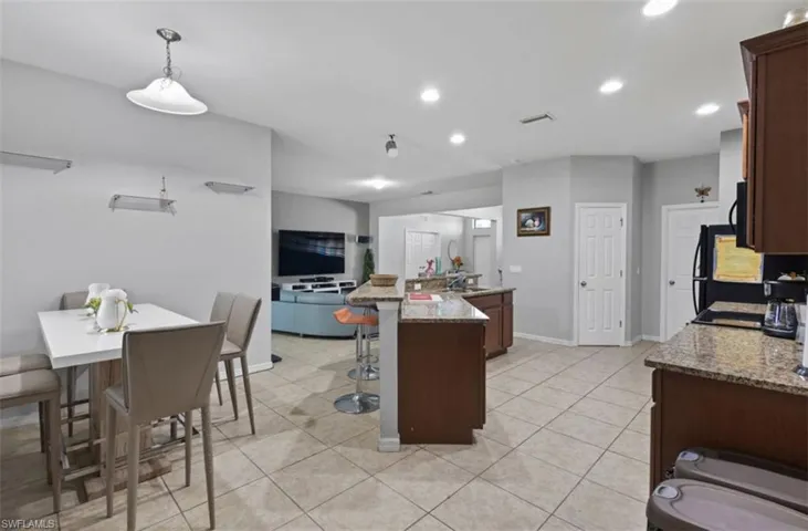 Kitchen featuring light stone counters, light tile floors, a center island, a breakfast bar, and pendant lighting