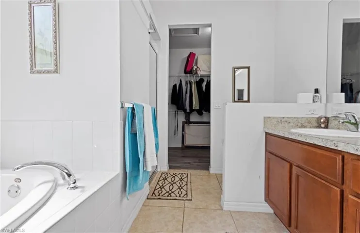 Bathroom with hardwood / wood-style flooring, tiled tub, and vanity
