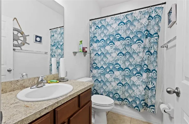 Full bathroom featuring tile flooring, shower / bath combination with curtain, vanity, and toilet