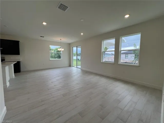 Unfurnished living room featuring recessed lighting, light wood-type flooring, and a chandelier