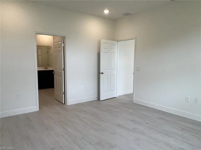 Unfurnished bedroom with light wood-style floors and connected bathroom