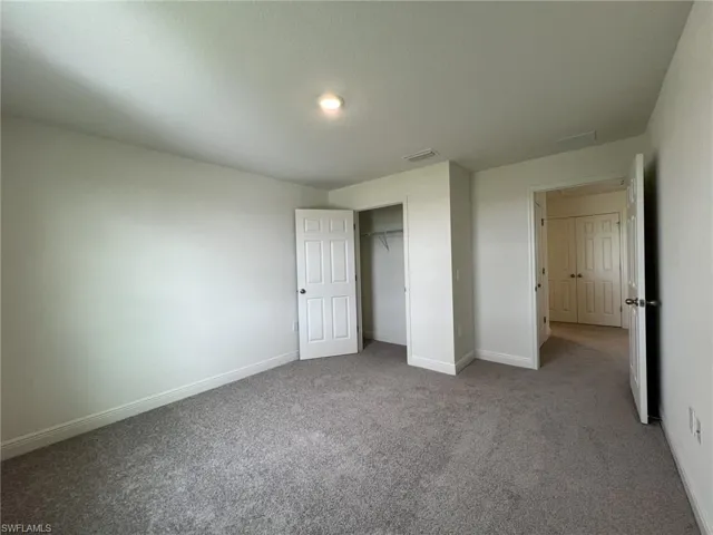 Unfurnished bedroom with light carpet and a closet