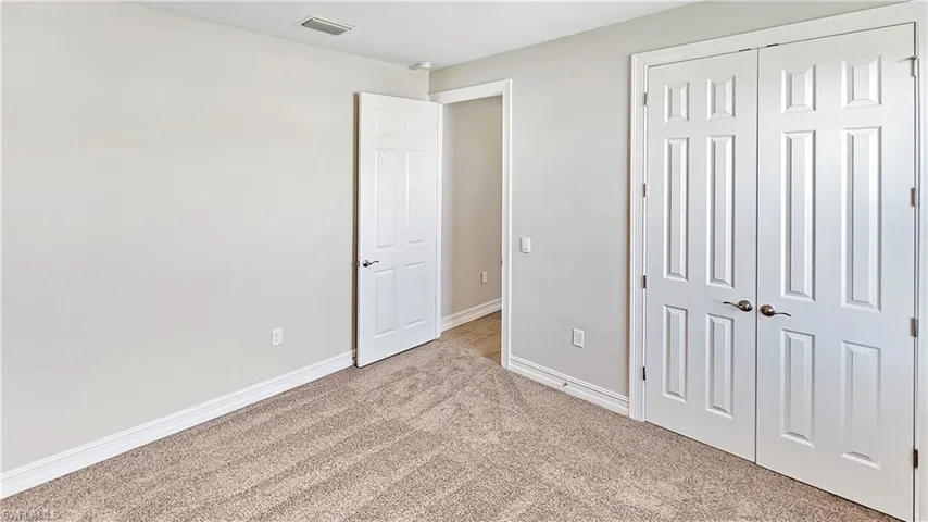 Unfurnished bedroom with a closet, carpet floors, visible vents, and baseboards