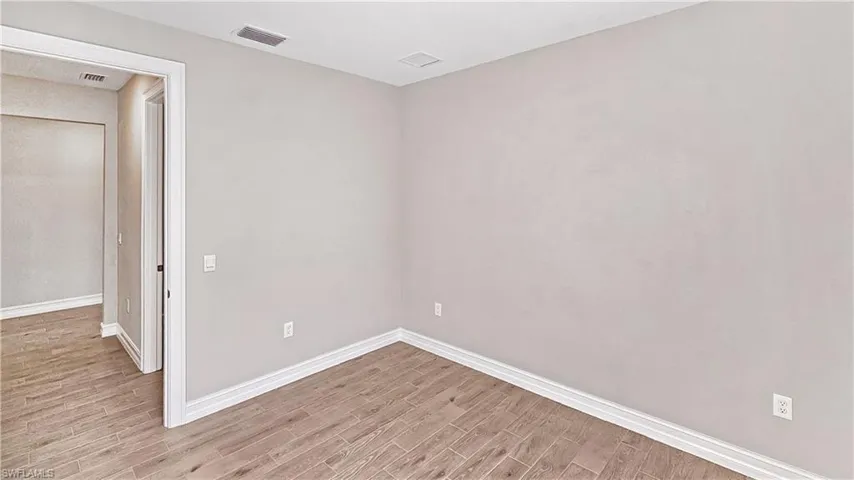 Empty room with baseboards, light wood-style floors, and visible vents