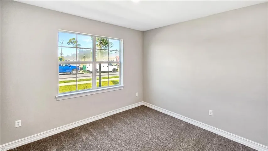 Empty room featuring baseboards and dark carpet