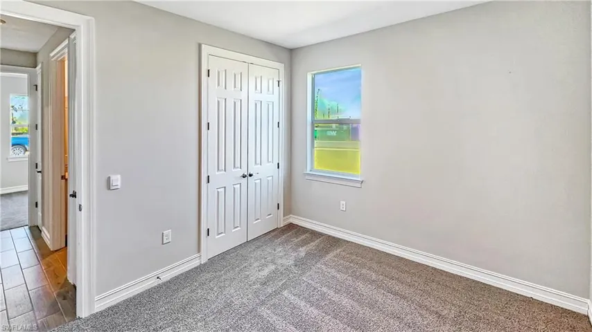 Unfurnished bedroom with multiple windows, a closet, and baseboards