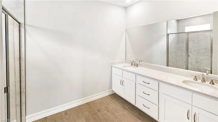 Bathroom featuring a tile shower, wood finished floors, and a sink