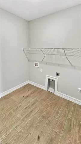 Washroom with washer hookup, baseboards, wood finished floors, and laundry area