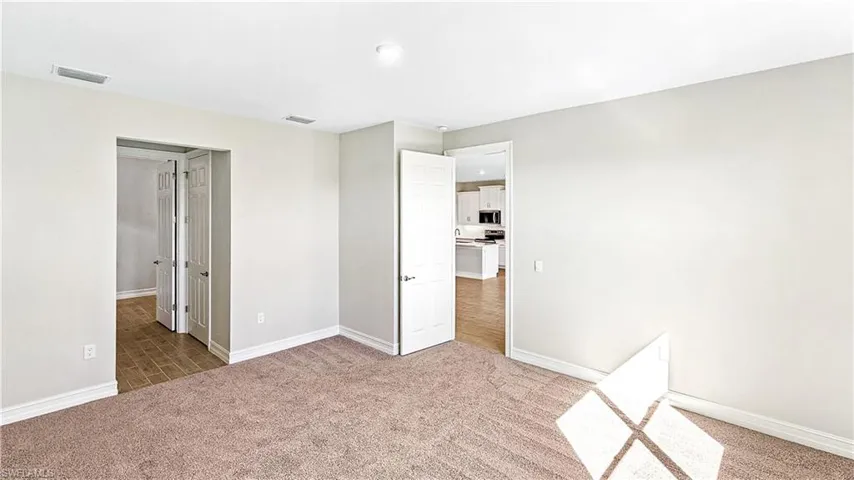 Unfurnished bedroom featuring carpet, baseboards, and visible vents