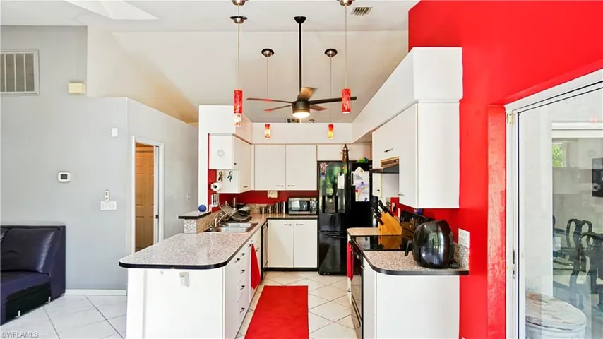 Kitchen with black appliances, extractor fan, a sink, a peninsula, and white cabinets