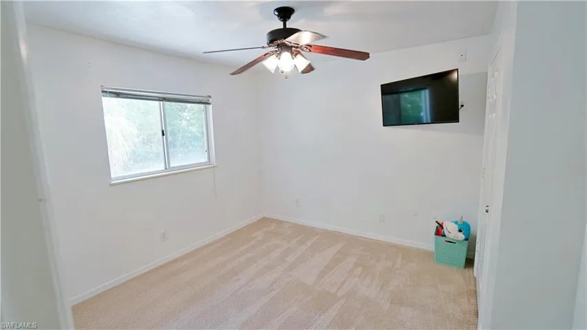 Empty room with ceiling fan, light colored carpet, and baseboards