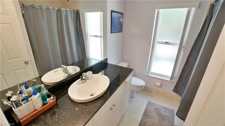 Bathroom with toilet, vanity, tile patterned floors, a shower with curtain, and baseboards