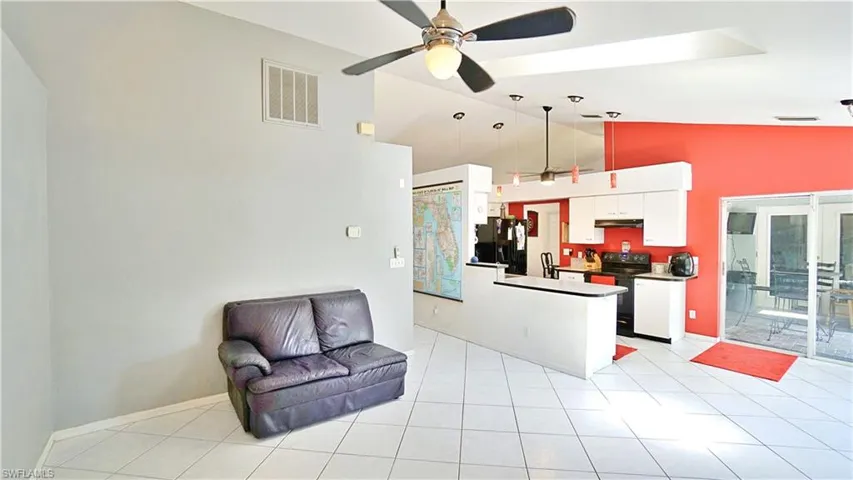Kitchen featuring black appliances, open floor plan, a ceiling fan, under cabinet range hood, and white cabinets