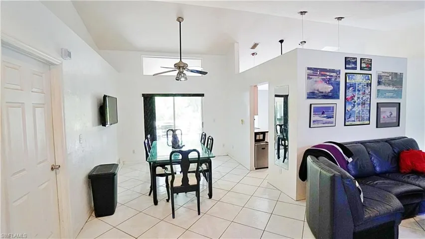 Dining area featuring vaulted ceiling, ceiling fan, and light tile patterned flooring