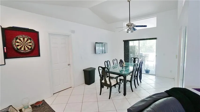Dining area featuring ceiling fan, vaulted ceiling, and light tile patterned floors