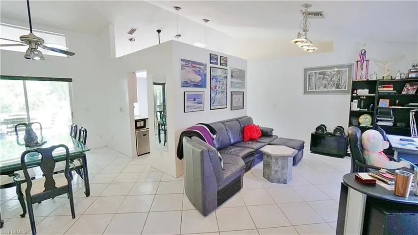 Living area featuring a ceiling fan, light tile patterned floors, and high vaulted ceiling