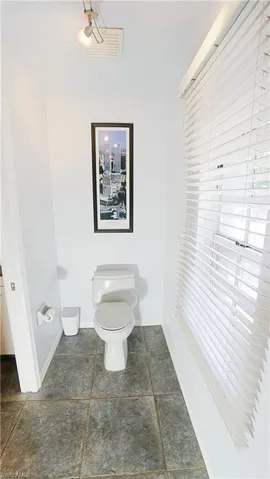 Bathroom with toilet, baseboards, and stone finish flooring