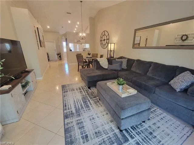 Living room featuring light tile patterned floors, a chandelier, and vaulted ceiling