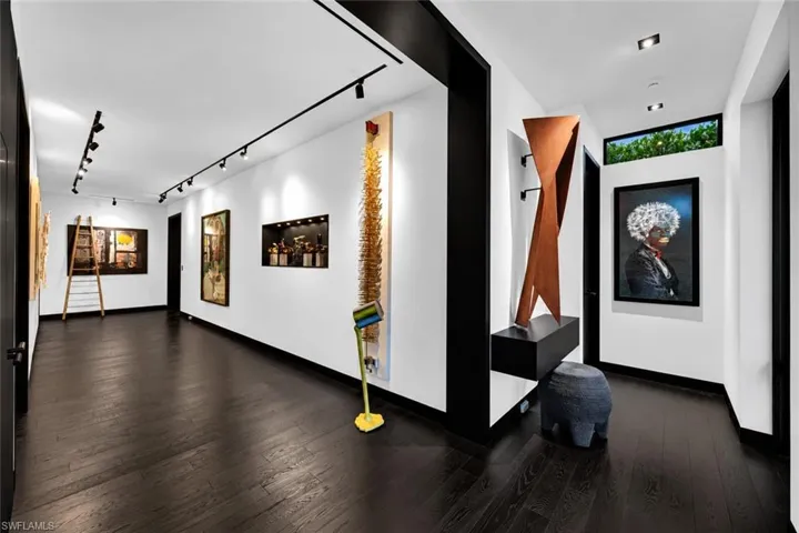 Hallway featuring dark wood-finish flooring, white walls, black trim, track lighting, and a transom window