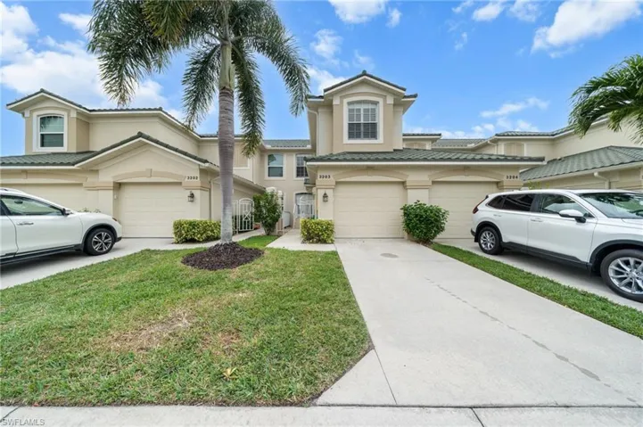 Mediterranean / spanish home with concrete driveway, stucco siding, a tiled roof, and a front lawn